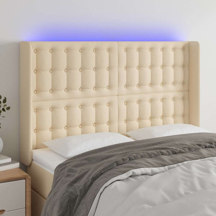 sengegavl med LED-lys 147x16x118/128 cm stof cremefarvet